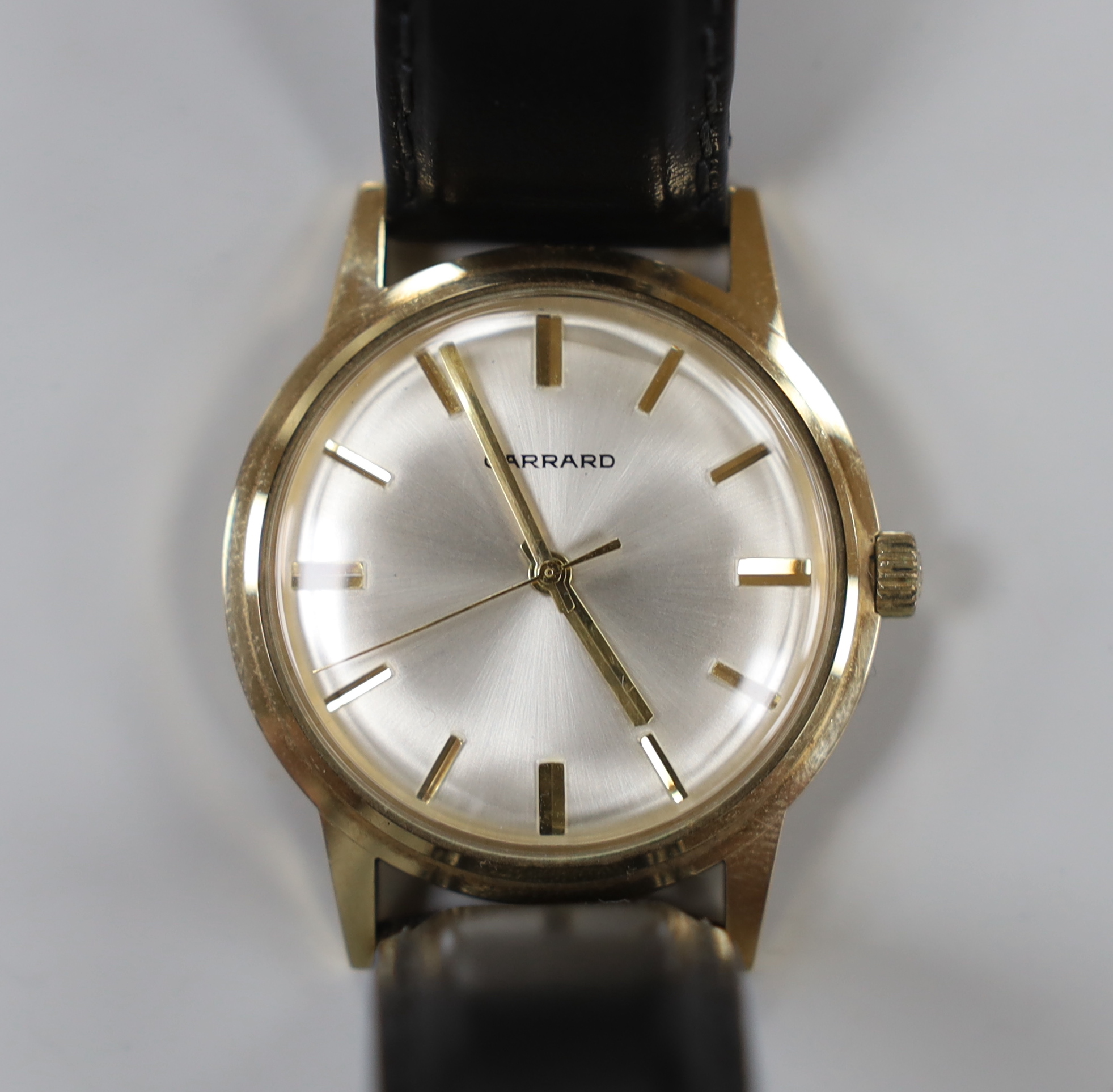 A gentleman's early 1970's 9ct gold manual wind wrist watch, retailed by Garrards, with case back inscription, on a leather strap.